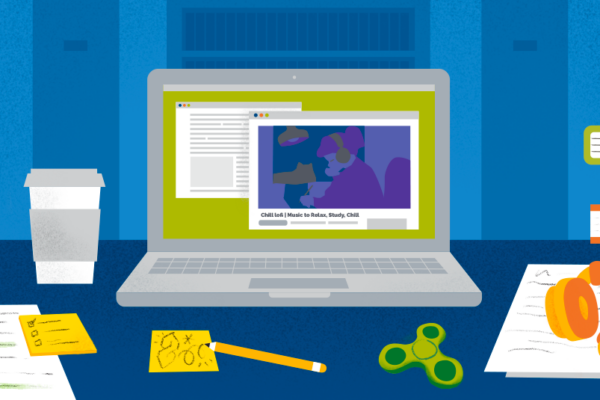 Laptop sitting on a desk, surrounded by books, papers, coffee, a fidget spinner, and headphones, denoting a study space.