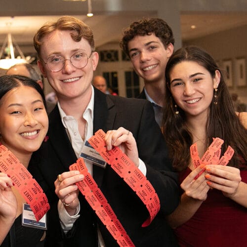 A group of people holding up reward tickets posing for the camera