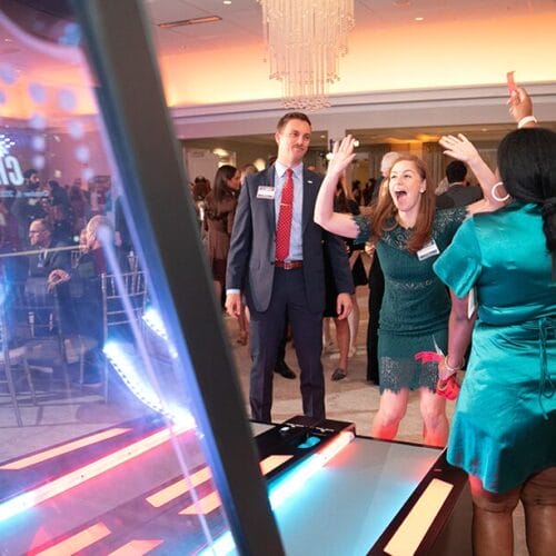 People looking happy while playing skee ball game